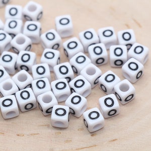 May include: A pile of white plastic letter beads with a black letter "O" on each bead.