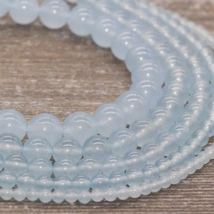 May include: A close-up of a strand of light blue round beads. The beads are arranged in a circle and are of varying sizes.
