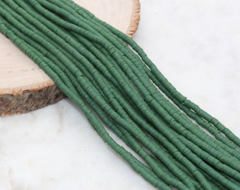 May include: A strand of green polymer clay beads. The beads are flat and round, and they are strung together on a clear thread.