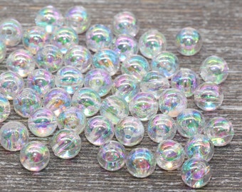 May include: A collection of iridescent clear glass beads. The beads are round and have a rainbow sheen.