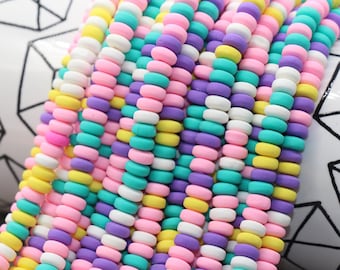 May include: A strand of colorful beads in pink, yellow, white, purple, and turquoise. The beads are round and have a matte finish.