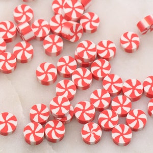 May include: A collection of red and white candy cane-shaped beads. The beads are round and have a swirl pattern.