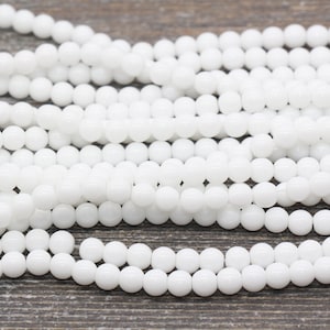 Peut inclure: Un brin de perles rondes en verre blanc. Les perles sont lisses et brillantes.