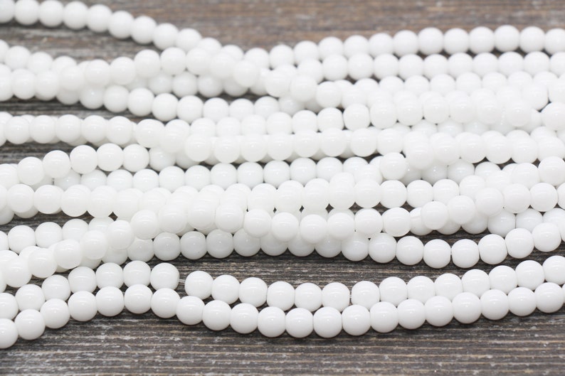 Peut inclure: Un brin de perles rondes en verre blanc. Les perles sont lisses et brillantes.