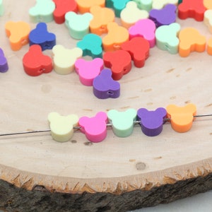 May include: A string of colourful bear-shaped beads on a wire. The beads are in a rainbow of colours, including yellow, pink, green, purple, and orange.