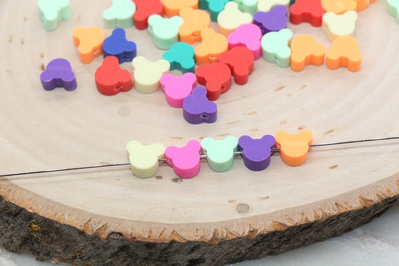 May include: A string of colourful bear-shaped beads on a wire. The beads are in a rainbow of colours, including yellow, pink, green, purple, and orange.
