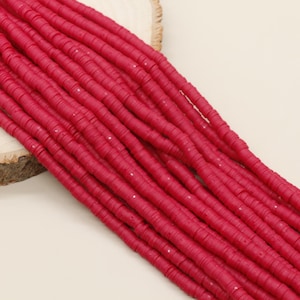 May include: A strand of bright pink round polymer clay beads. The beads are flat and have a slightly textured surface.