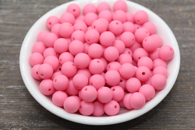 May include: A bowl filled with pink silicone beads. The beads are round and have a matte finish.