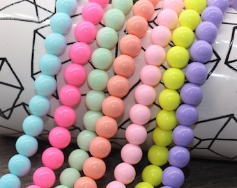 May include: A strand of colorful round beads in shades of blue, pink, green, orange, yellow, and purple. The beads are arranged in rows, creating a rainbow effect.