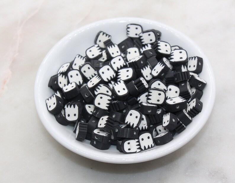 May include: A bowl filled with black and white plastic beads. Each bead has a small, white, cartoon face with a toothy grin.