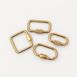 May include: Four gold-toned metal carabiner clips in various shapes, including one square and three rectangular designs. Each clip features a functional screw-gate locking mechanism with a textured, cross-hatched grip surface for secure closure.