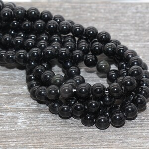 May include: A strand of black gemstone beads, likely obsidian, with a smooth, polished finish. The beads are round and uniform in size, creating a consistent look.