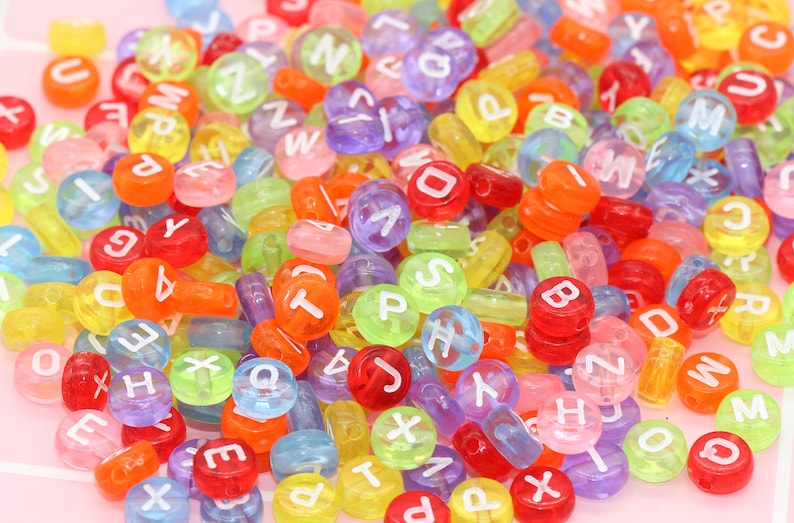 May include: A large assortment of colourful plastic alphabet beads. The beads are translucent and have white letters on them.