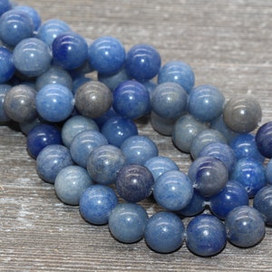Pode incluir: Um fio de contas de pedra preciosa de quartzo azul. As contas redondas apresentam tons de azul e cinza. As contas s&atilde;o enfiadas, para um colar ou pulseira.