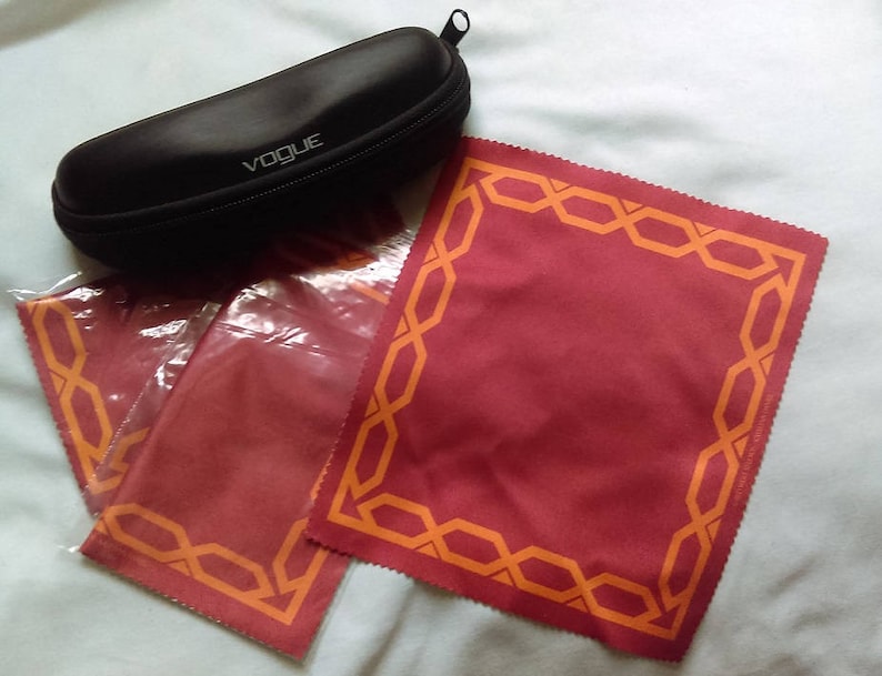 May include: A black eyeglass case with the word "VOGUE" printed on it, and three red microfiber cleaning cloths with orange patterned borders.