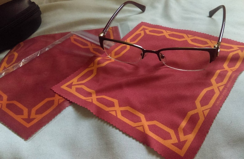 May include: A pair of brown eyeglasses with a red and orange patterned microfiber cleaning cloth. The cloth has a decorative border.