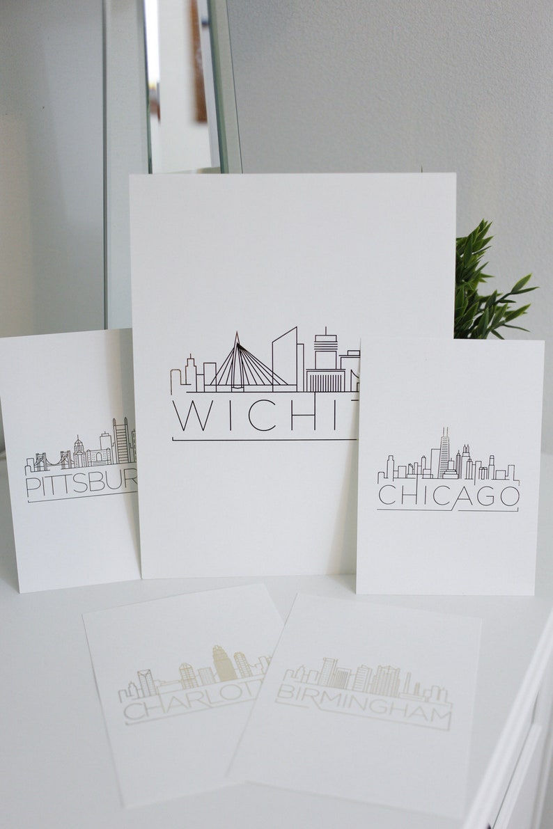 May include: Four white cards with black outlines of city skylines and the city name printed below. The cities are Pittsburgh, Wichita, Chicago, and Charlotte.