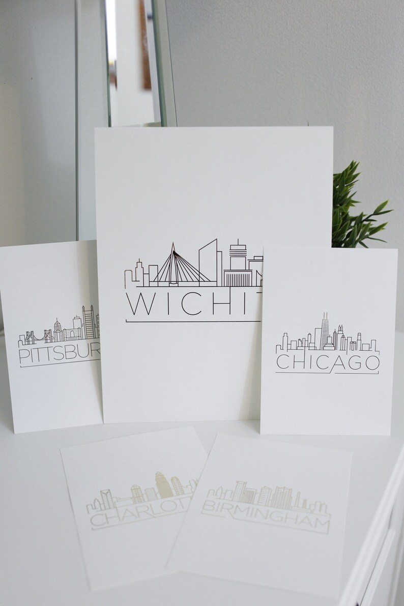 May include: Four white cards with black outlines of city skylines and the city name printed below. The cities are Pittsburgh, Wichita, Chicago, and Charlotte.