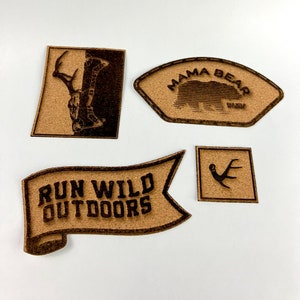 May include: Four wooden patches with different designs. The first patch features a deer with antlers, the second patch features a bear with the text "Mama Bear Run Wild Outdoors", the third patch features a banner with the text "Run Wild Outdoors", and the fourth patch features a set of antlers.