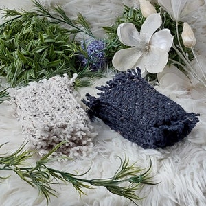 Peut inclure: Deux carrés de tissu tricoté avec des bords effilochés. Un carré est blanc et l'autre est gris foncé. Les carrés sont sur une surface blanche et moelleuse.