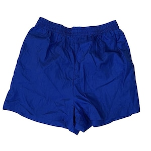 May include: Bright blue athletic shorts with an elastic waistband. The shorts are made of a lightweight, slightly textured fabric. The shorts are a solid color and appear to be unworn.