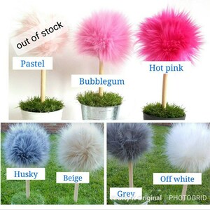 May include: A collection of decorative faux fur pom-pom trees on wooden dowels, each set in a small pot with artificial grass. Colors include pastel, bubblegum, hot pink, husky blue, beige, grey, and off-white. Text labels identify each color.