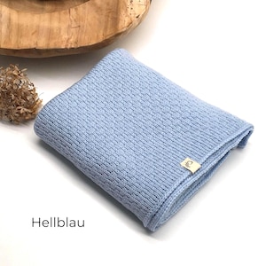 *Handgestrickte Babydecke in Hellblau mit feiner Strickstruktur, weiches Naturgarn mit Joseda-Label, dekoriert mit Trockenblumen und Holzschale auf hellem Hintergrund, Farbbezeichnung „Hellblau“ im Bild