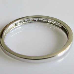 May include: A silver band with a row of small diamonds set in the center.