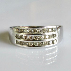 May include: A silver band ring with three rows of small, clear diamonds.