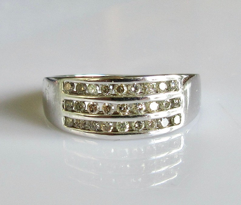 May include: A silver band ring with three rows of small, clear diamonds.