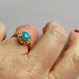 May include: A gold ring with a turquoise stone set in a delicate floral design.