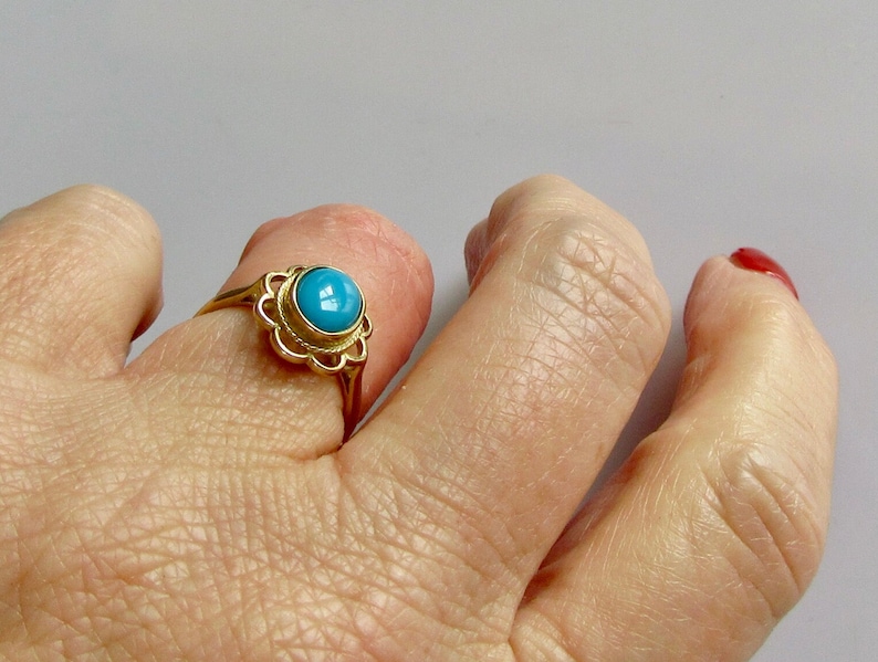 May include: A gold ring with a turquoise stone set in a delicate floral design.