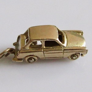 May include: A silver charm in the shape of a vintage car. The charm has a detailed design and a loop for attaching to a bracelet or necklace.