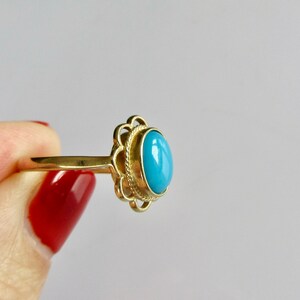 May include: A gold ring with a blue oval gemstone set in a decorative filigree design.