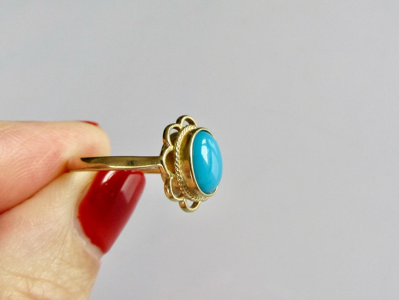 May include: A gold ring with a blue oval gemstone set in a decorative filigree design.