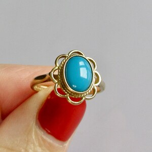 May include: A gold ring with a blue oval gemstone set in a delicate floral design.