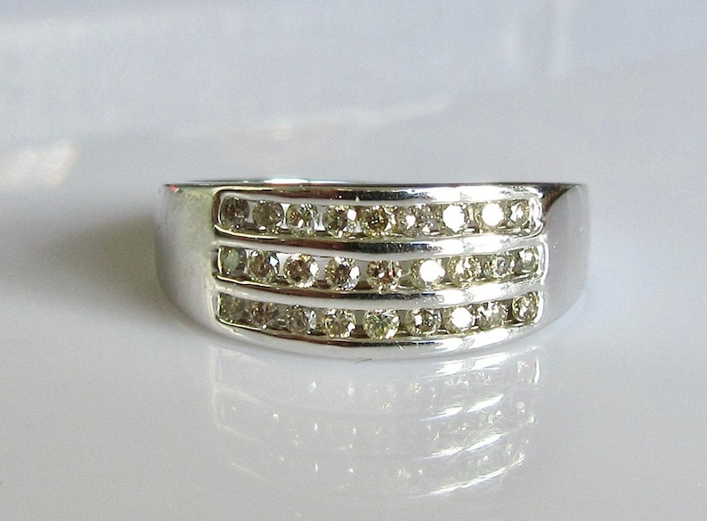 May include: A silver band ring with three rows of small, clear diamonds.