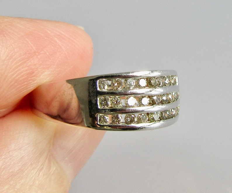 May include: A silver band ring with three rows of small, clear diamonds.