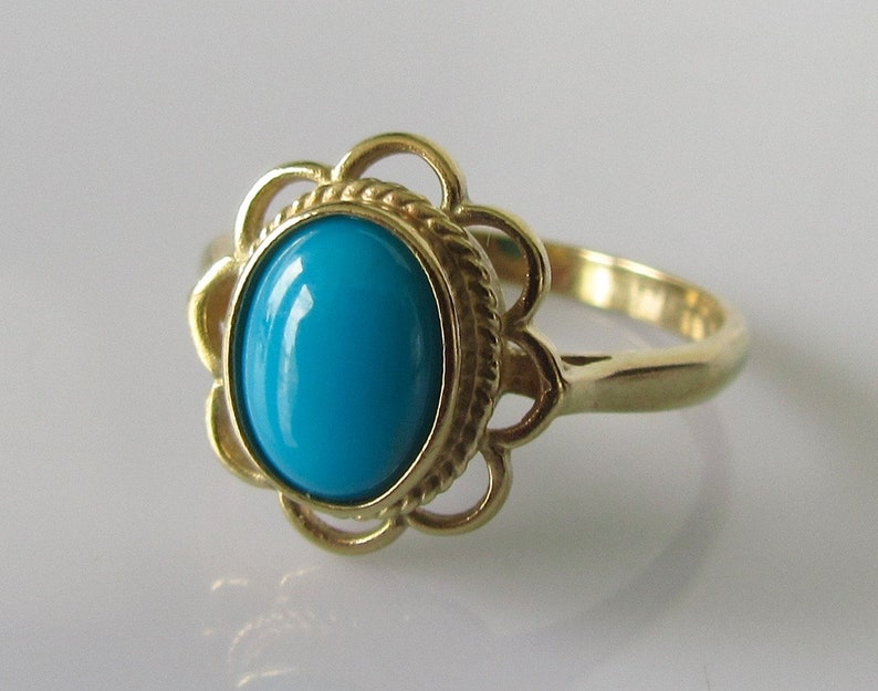 May include: A gold ring with a turquoise gemstone set in a floral design.