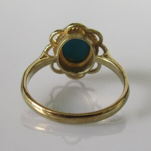 May include: A gold ring with a teal oval stone set in a floral design.