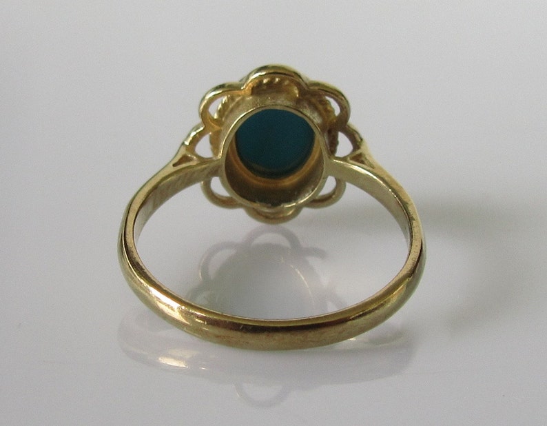 May include: A gold ring with a teal oval stone set in a floral design.