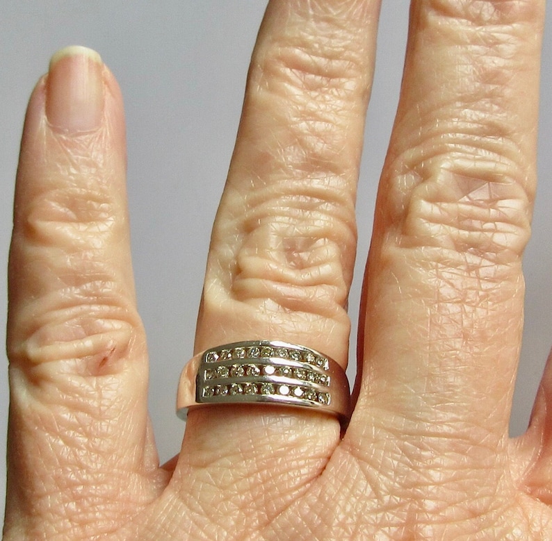 May include: A silver band ring with three rows of small, clear diamonds.
