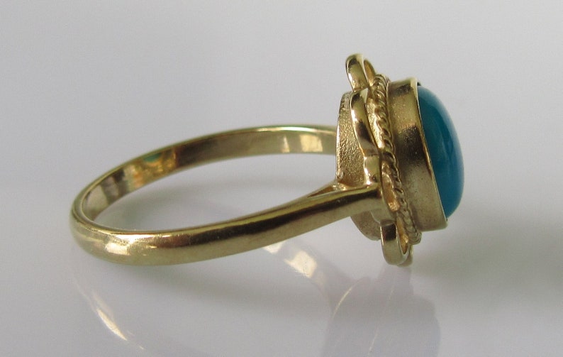 May include: A gold ring with a teal oval gemstone set in a rope-like design.