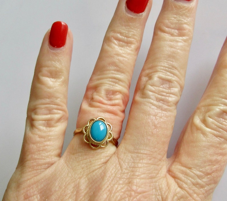 May include: A gold ring with a turquoise stone set in a floral design.