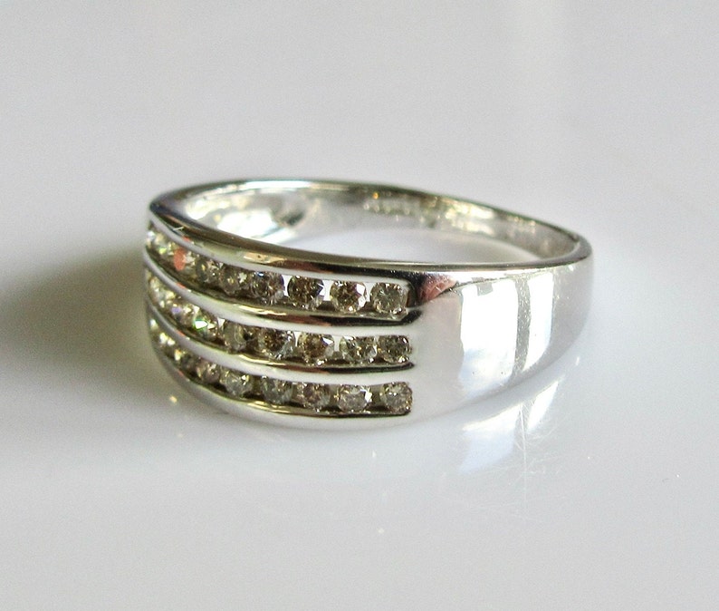 May include: A silver band ring with three rows of small, clear diamonds.