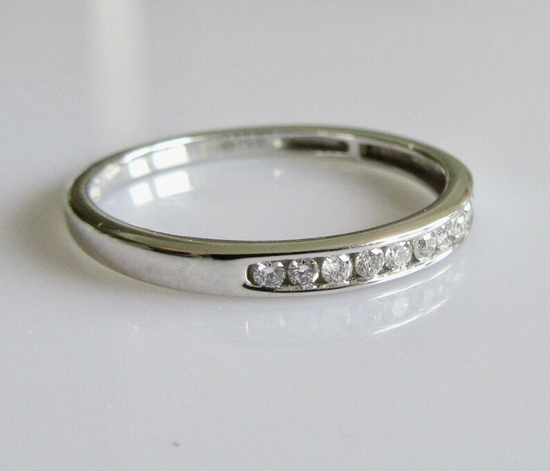 May include: A thin silver band with a row of small diamonds set in a channel setting.