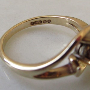 May include: A gold ring with a red gemstone and a smaller diamond accent. The inside of the band is stamped with "9 375" and a hallmark.