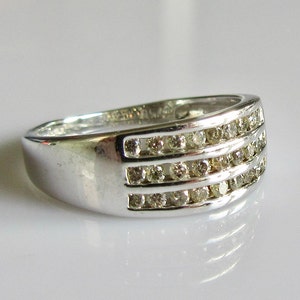 May include: A silver band ring with three rows of small, clear diamonds.