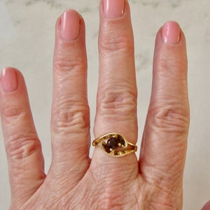 May include: A gold ring with a brown gemstone set in a leaf-shaped design.