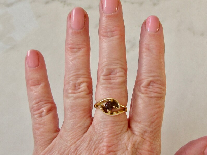 May include: A gold ring with a brown gemstone set in a leaf-shaped design.